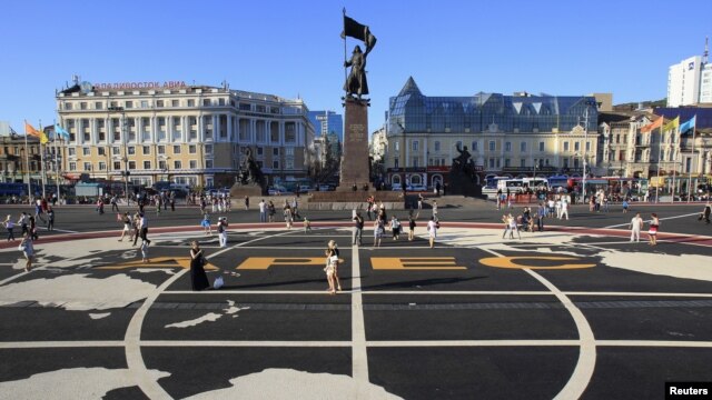 People walk over a tarmac with the Asia-Pacific Economic Cooperation (APEC) logo printed on it, in a central square of Vladivostok, Russia, September 6, 2012.