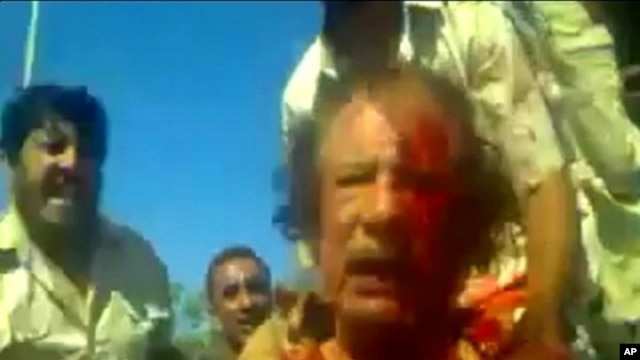 Image taken from amateur video posted on a social media website and obtained by Reuters, October 21, 2011, shows former Libyan leader Moammar Gadhafi, covered in blood, after his capture by NTC fighters in Sirte.