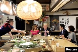 El presidente de EE.UU., Donald Trump, con la primera dama Melania Trump, recibe un plato con comida de un chef durante una cena con el primer ministro de Japón Shinzo Abe y su esposa Akie Abe en Tokio. Mayo 26 de 2019.