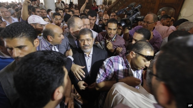 The Muslim Brotherhood's presidential candidate, Mohamed Morsi, center, is surrounded by his supporters after he participated in Friday prayers in Amr Ibn Al-As mosque in Cairo, Egypt, Friday, June 22, 2012.