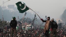 A supporter of Tahir-ul Qadri waves a Pakistani flag as he walks on a container on the third day of protests in Islamabad, Pakistan, January 16, 2013.