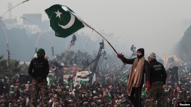 A supporter of Tahir-ul Qadri waves a Pakistani flag as he walks on a container on the third day of protests in Islamabad, Pakistan, January 16, 2013.