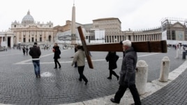 Pilgrims carry a cross as they arrive to pray in front of Saint Peter's Basilica at the Vatican in Rome, Feb. 11, 2013.