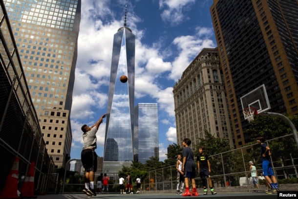 One World Trade Center towers over lower Manhattan as children play basketball in New York August 26, 2015. REUTERS/Brendan McDermid