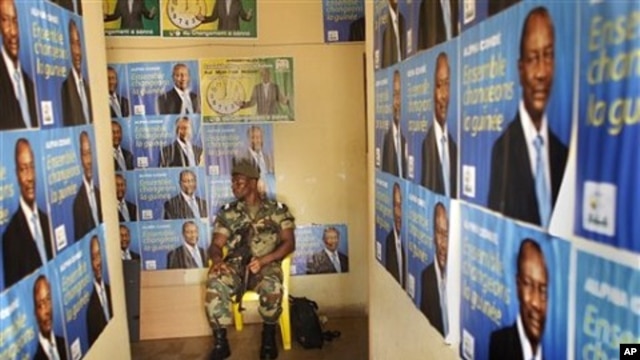 A soldier sits amidst election posters of Presidential candidate Alpha Conde in the entrance of the Guinean People Rally (RPG) headquarters in Guinea's capital Conakry Saturday 18 Sept. 2010