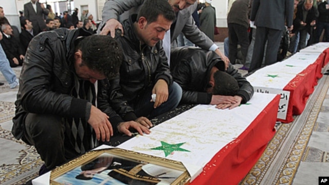 Syrian men mourn over the coffin of one of 11 Syrian police officers who were killed in an explosion in the Midan neighborhood, during a mass funeral procession at Al-Hassan mosque, in Damascus, January 7, 2011.