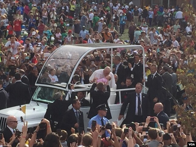 Pope Francis kisses a baby from his popemobile near Independence Hall, Philadelphia, Sept. 26, 2015. (J. Socolovsky/VOA)