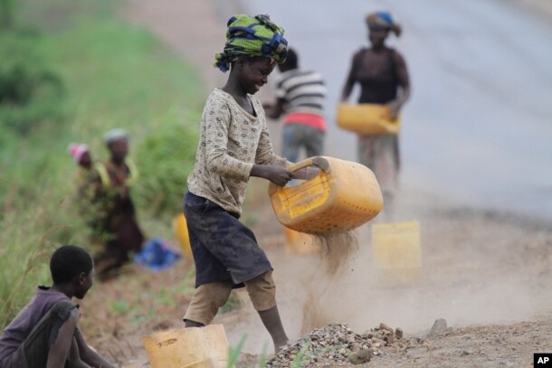FILE - A girl sifts roadside sand to separate the stones to sell as building material in Inchope, northern Mozambique.