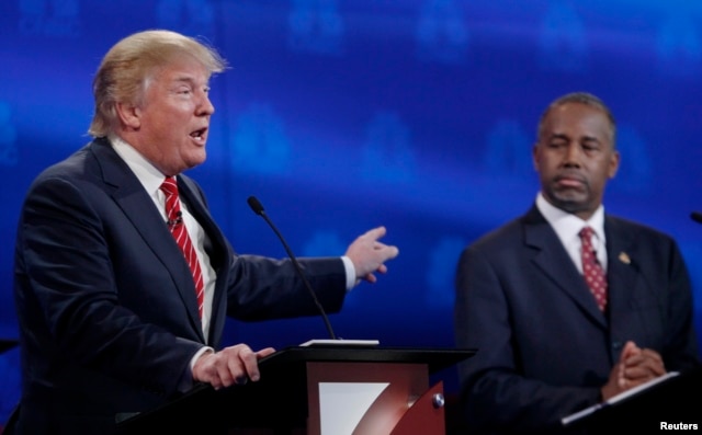 U.S. presidential candidate and businessman Donald Trump, left, speaks as Ben Carson, a retired neurosurgeon, listens at the 2016 U.S. Republican presidential candidates debate held by CNBC in Boulder, Colo., Oct. 28, 2015.