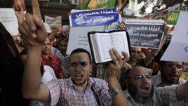People shout and hold slogans in front of the U.S. embassy during a protest in Cairo, Egypt, September 11, 2012. 