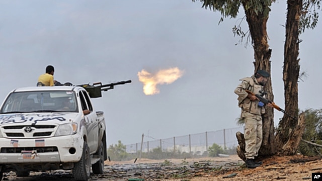 Libyan revolutionary fighters fire with a machine gun while attacking pro-Gadhafi forces at the Ouagadougou conference center of Sirte, Libya, October 7, 2011.