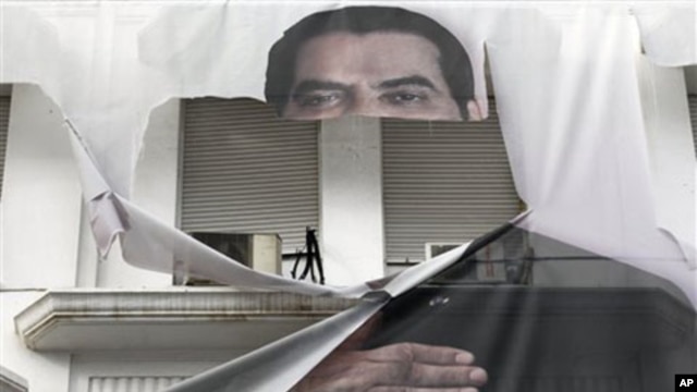 A torn banner of former Tunisian President Zine El Abidine Ben Ali is seen in the center of Tunis, 16 Jan 2011