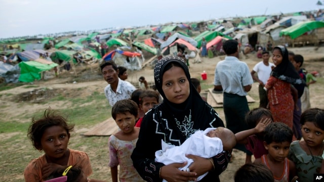 FILE - An internally displaced Rohingya woman holds her newborn baby surrounded by children in the foreground of makeshift tents at a camp for Rohingya people in Sittwe, northwestern Rakhine State, Burma.