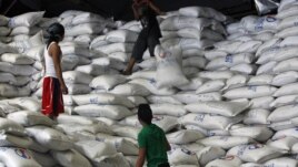 A worker passes a sack of rice to other workers inside a National Food Authority (NFA) warehouse in Taguig City, south of Manila, the Philippines, March 26, 2012. 