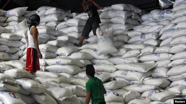 A worker passes a sack of rice to other workers inside a National Food Authority (NFA) warehouse in Taguig City, south of Manila, the Philippines, March 26, 2012. 