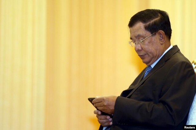 FILE - Cambodia's Prime Minister Hun Sen looks at his smartphone at a ceremony in Phnom Penh, Feb. 25, 2016.