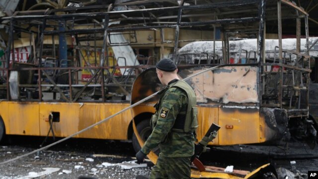 Phiến quân đòi ly khai thân Nga đi ngang qua một trạm xe buýt bị phá hủy sau một vụ pháo kích ở Donetsk, Ukraina, ngày 11/2/2015.