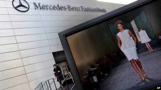 A designer's runway show is shown on a television screen outside the Fashion Week venue at New York's Lincoln Center,  Feb. 6, 2013.