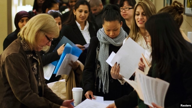U.S. job seekers adjust their paperwork as they wait in line to attend a job fair in New York, February  28, 2013. 
