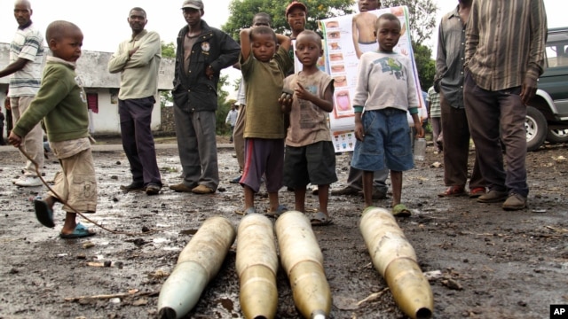 Congolese citizens look at tank shells lying next to roadside, left behind by retreating government troops as they fled assault by M23 rebels, in eastern Congo, Nov. 21, 2012.