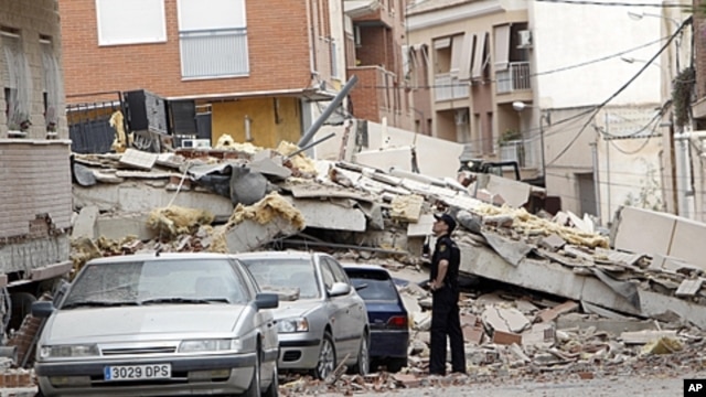 A police officer looks at the damage in Lorca, Spain a  day after an earthquake hit the region, May 12, 2011.