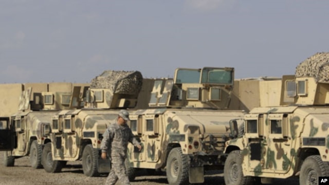U.S. army soldiers walk past military armored vehicles ready to be shipped out of Iraq at Camp Victory Baghdad, Iraq, November 7, 2011.