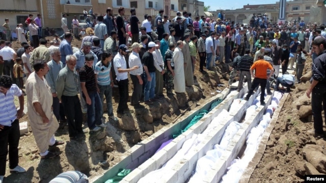 People gather at a mass burial for the victims purportedly killed during an artillery barrage from Syrian forces in Houla in this handout image provided by Shaam News Network, May 26, 2012.