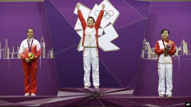 China's Yi Siling, center, celebrates winning the gold medal in the women's 10-meter air rifle event, alongside silver medalist Poland's Sylwia Bogacka, left, and bronze medalist China's Yu Dan, right, at the 2012 Summer Olympics in London, Saturday, July