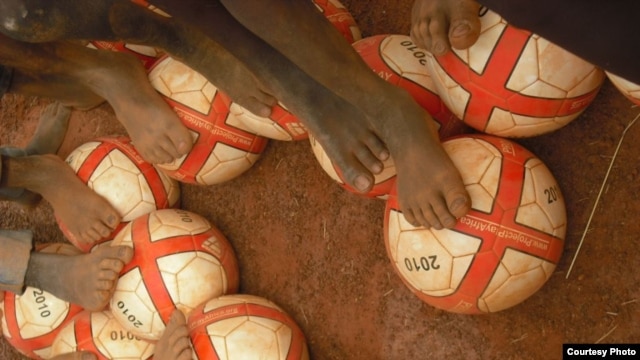 Children in Benin get a foot on their new soccer balls from Project Play Africa in 2010. (Courtesy Project Play Africa)