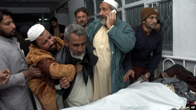 Pakistanis mourn next to the body of their relative killed in a suicide bombing, at a local hospital in Peshawar, Pakistan, Saturday, Dec. 22, 2012. 