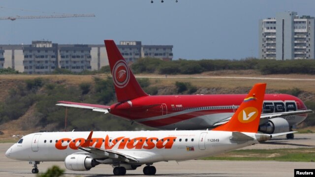 FILE - Airplanes wait their turn to take off on a runway of the Simon Bolivar airport in La Guaira, outside Caracas. 