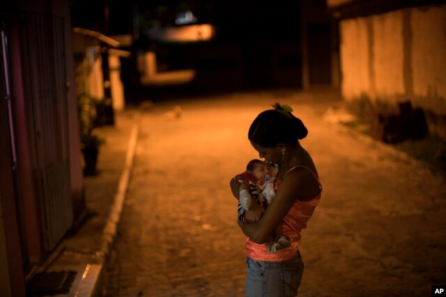 Cô Daniele Ferreira dos Santos ôm cậu con trai Juan Pedro, bị tật nhỏ đầu, bên ngoài ngôi nhà của cô ở Brazil. Santos chưa bao giờ bị nhiễm virut Zika nhưng cô cho rằng virut này đã gây nên tật nhỏ đầu của con cô.