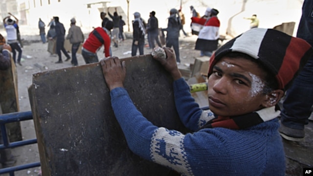 An Egyptian boy takes cover while others throw stones during clashes with the security forces near the interior Ministry in downtown Cairo, Egypt, February 3, 2012.