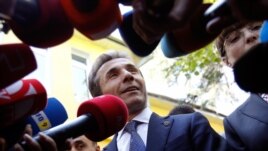 Leader of the opposition Georgian Dream coalition Bidzina Ivanishvili (C) addresses the media near his wife Eka Khvedelidze (R), who voted at a polling station during the parliamentary election, in Tbilisi October 1, 2012.