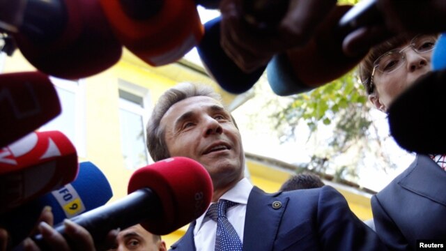 Leader of the opposition Georgian Dream coalition Bidzina Ivanishvili (C) addresses the media near his wife Eka Khvedelidze (R), who voted at a polling station during the parliamentary election, in Tbilisi October 1, 2012.