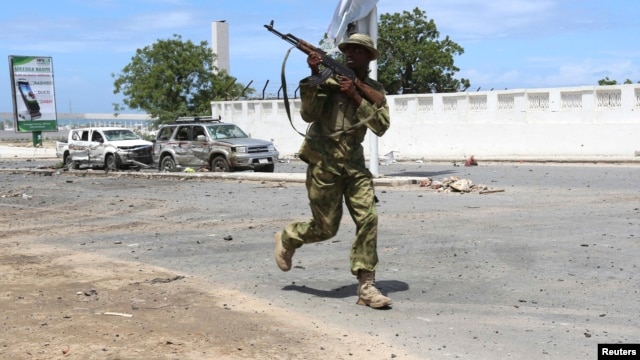 FILE - Somali government soldier runs to take position in front of the Parliament during fighting between them and al-Shabab militia in the capital Mogadishu, May 24, 2014. 