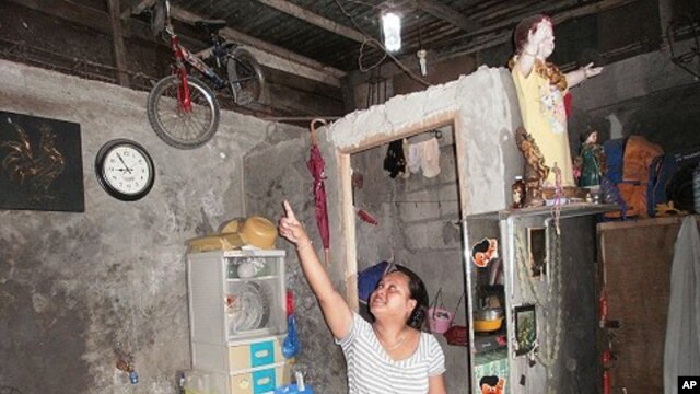 Sheila Royeras admires the soda bottle solar bulbs that were installed in her shanty home. The bulbs are made out of a soda bottle, purified water and some bleach. San Juan City, Metropolitan Manila, Philippines,  November 18, 2011.