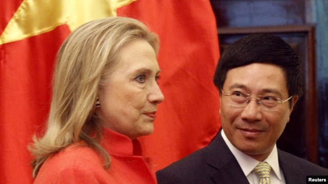 Vietnam's Foreign Minister Pham Binh Minh (R) looks at U.S. Secretary of State Hillary Clinton as they walk to the meeting room at the Government Guest House in Hanoi, July 10, 2012. 