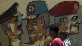 People walk in front of a wall sprayed with stencilled paintings depicting the Egyptian military council members in Tahrir Square in Cairo May 24, 2012.