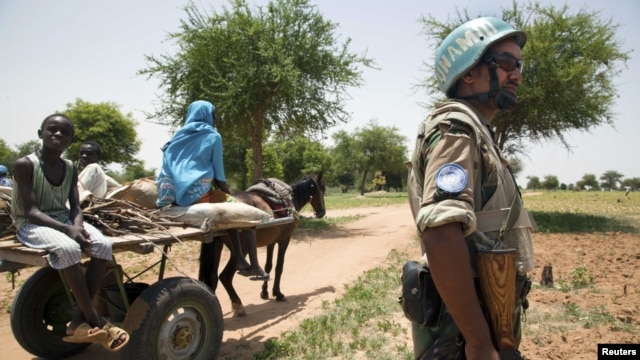 UNAMID peacekeeper Sergent Kindu Tarekegn, from Adigrat, Ethiopia, escorts a family that is returning home after farming outside Gereida, South Darfur, July 25, 2012. 