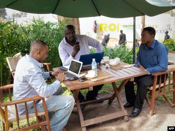 FILE - Men work on their laptops at the Endiro Cade in Kampala, Uganda.