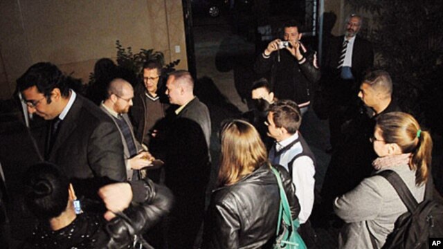 In this Thursday, December 29, 2011, file photo, workers from one of the US non-governmental organizations, the National Democratic Institute, wait as Egyptian officials raid their office in Cairo.