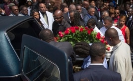 Lesley McSpadden (R, in red) watches as the casket containing the body of her son Michael Brown lifted into a hearse after his funeral services at Friendly Temple Missionary Baptist Church, St. Louis, Missouri, August 25, 2014.