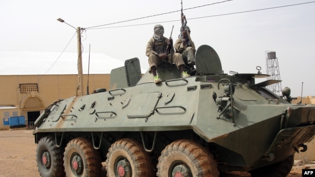 Fighters of the Islamic group, the al-Qaeda offshoot MUJAO stand guard on a tank abandoned by the Malian Army, near Gao airport, August 7, 2012.
