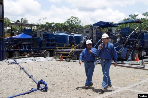 Workers walk past machinery at Miranda Port in Tiputini, Ecuador, Sept. 7, 2016.