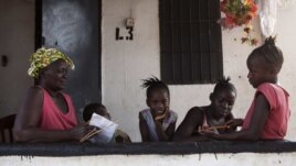 A grandmother gives her grandchildren school lessons on their porch in Sierra Leone's capital Freetown, April 24, 2012.