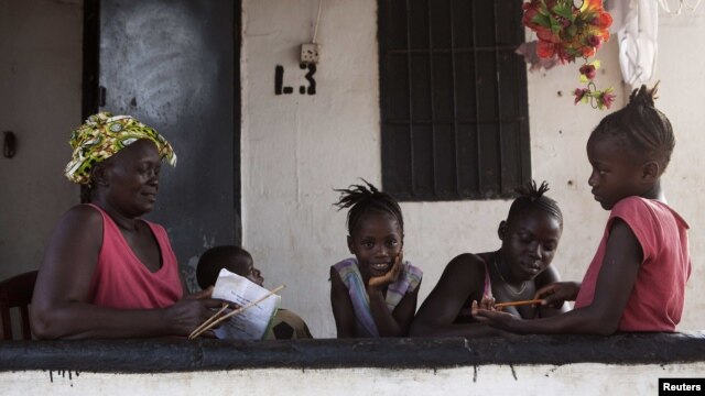 A grandmother gives her grandchildren school lessons on their porch in Sierra Leone's capital Freetown, April 24, 2012.