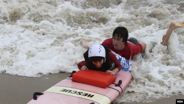 Austin Bramson takes a ride on a surfboard with the help of a Best Day at the Beach volunteer. (VOA/D. Grunebaum)