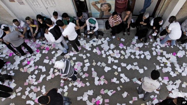 In this photo taken during a government-organized tour, Syrian campaign workers wait outside a polling station during the parliamentary elections, in Damascus, Syria, May 7, 2012.