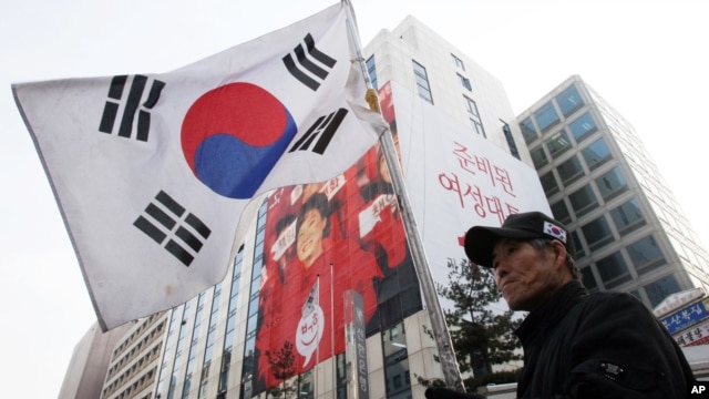 An anti-communist person holds a national flag during a rally to celebrate the victory of  South Korea's president-elect Park Geun-hye of Saenuri Party in front of the party headquarters in Seoul, South Korea, December 20, 2012.